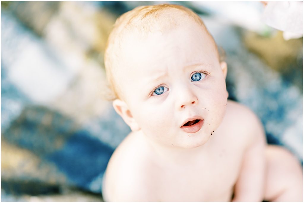 one year old boy looking up at camera with big blue eyes