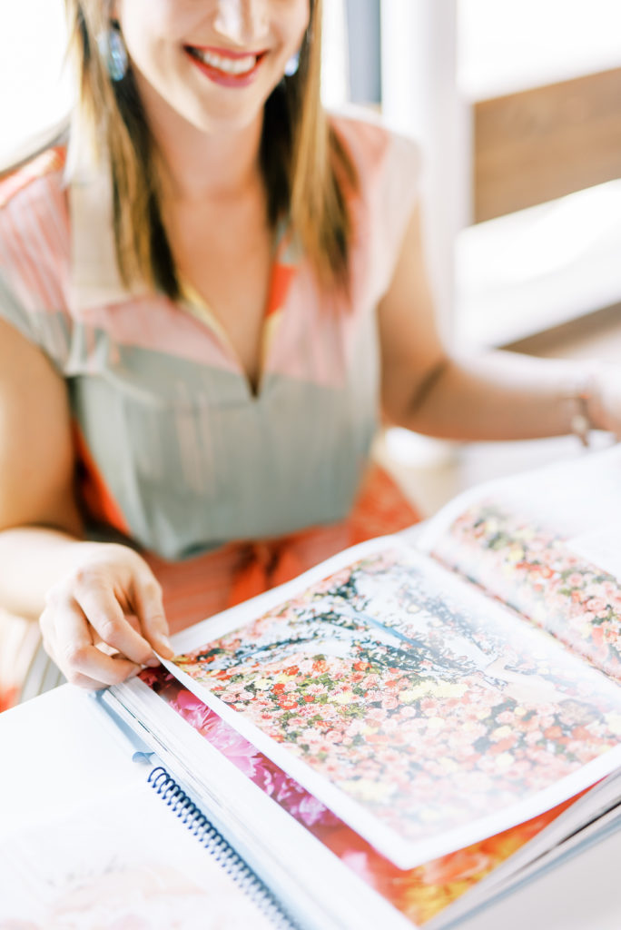 A smiling Terra Nickelson flips through a magazine of colorful flowers