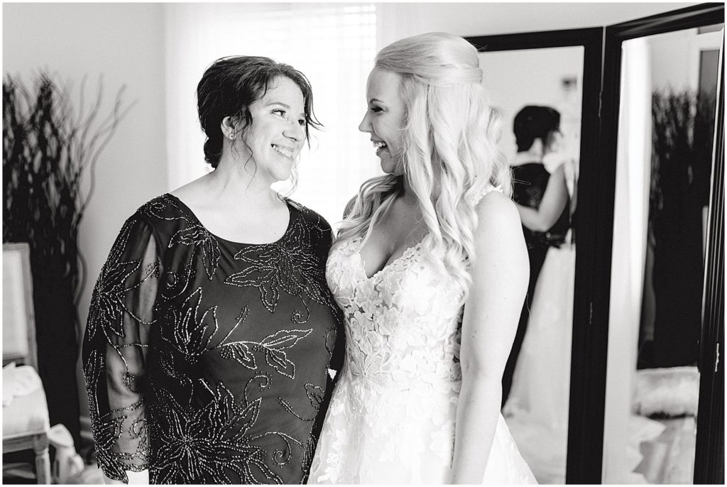 black and white image of bride and mom smiling at each other on wedding day