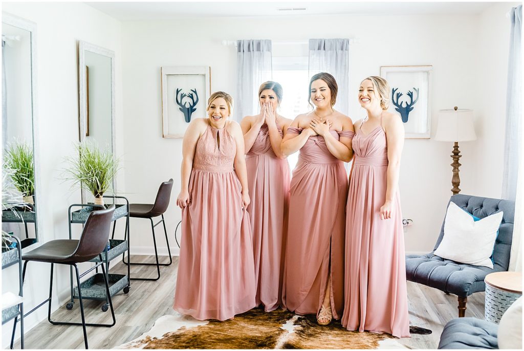 bridesmaids smiling and crying seeing bride for the first time