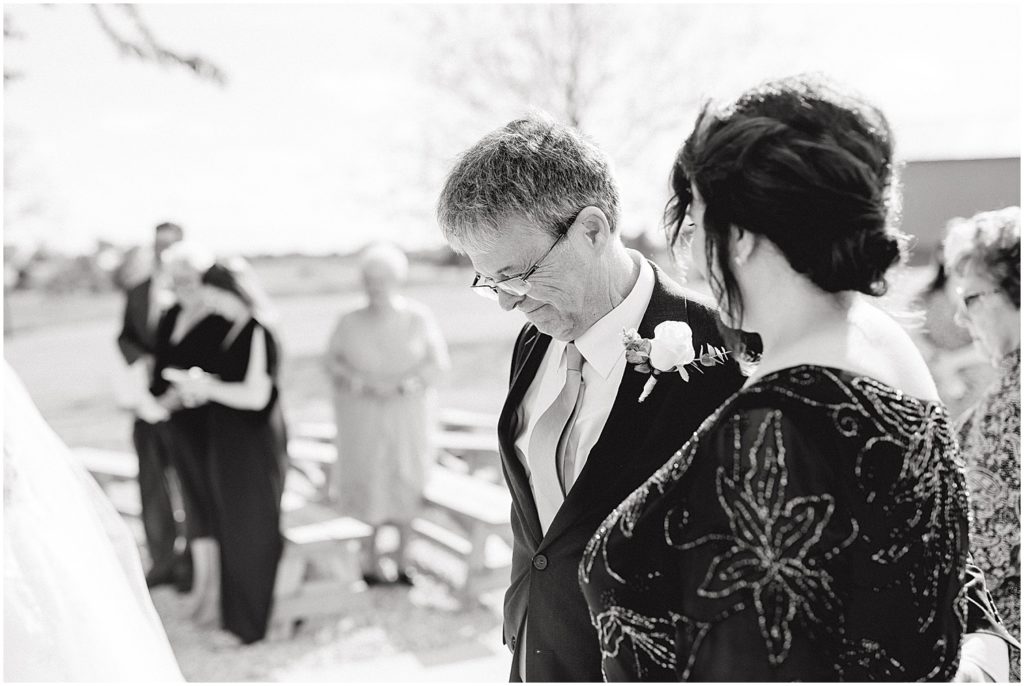 black and white image of dad smiling after walking bride down the aisle