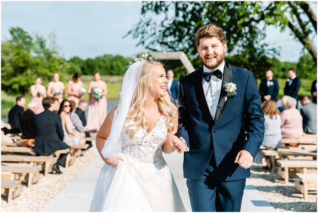 bride and groom smiling as they walk down the aisle during wedding ceremony