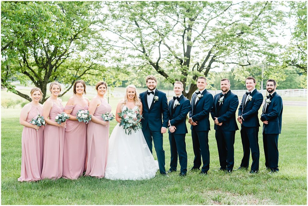 wedding party standing in grass in navy blue and pink dresses