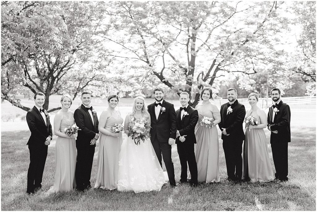 black and white image of wedding party standing under trees