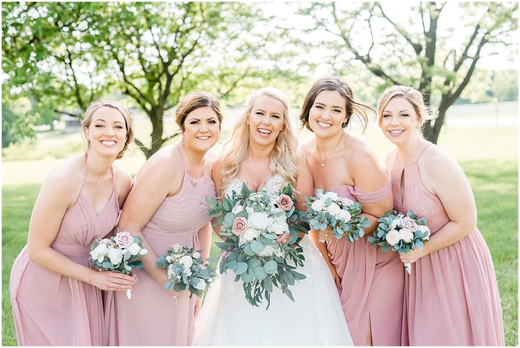 bride and bridesmaids smiling for camera with bouquets