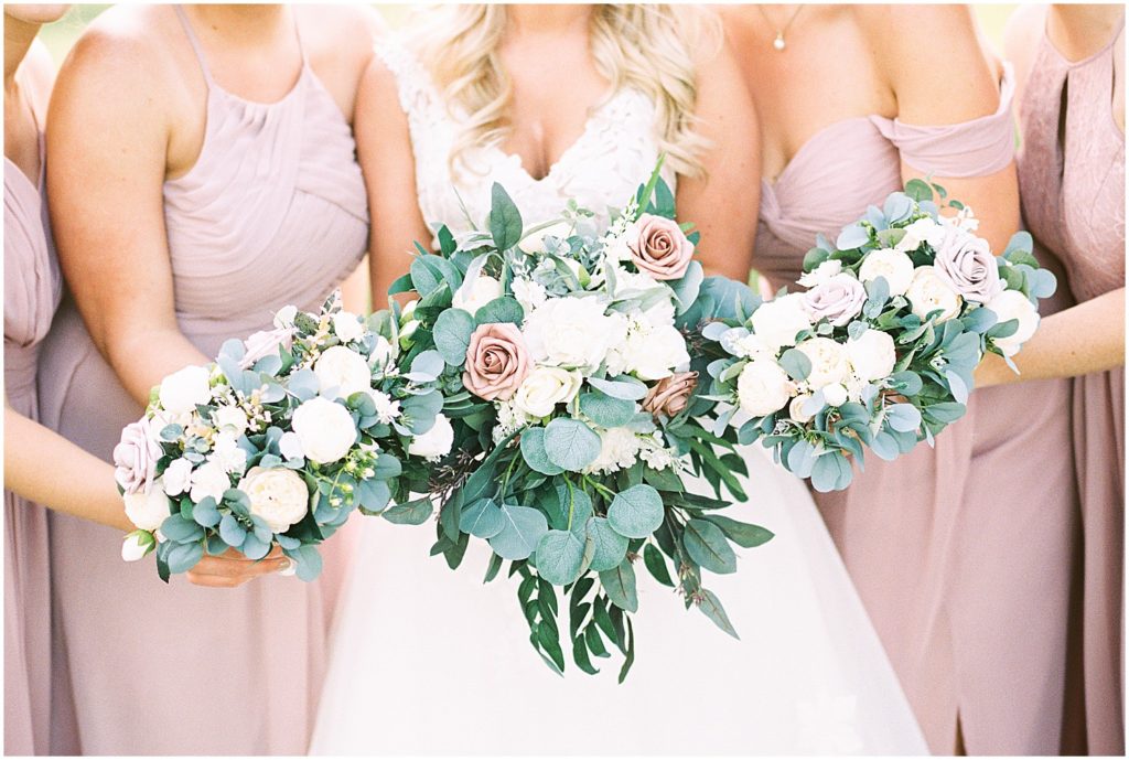 bride and bridesmaids holding flowers towards camera