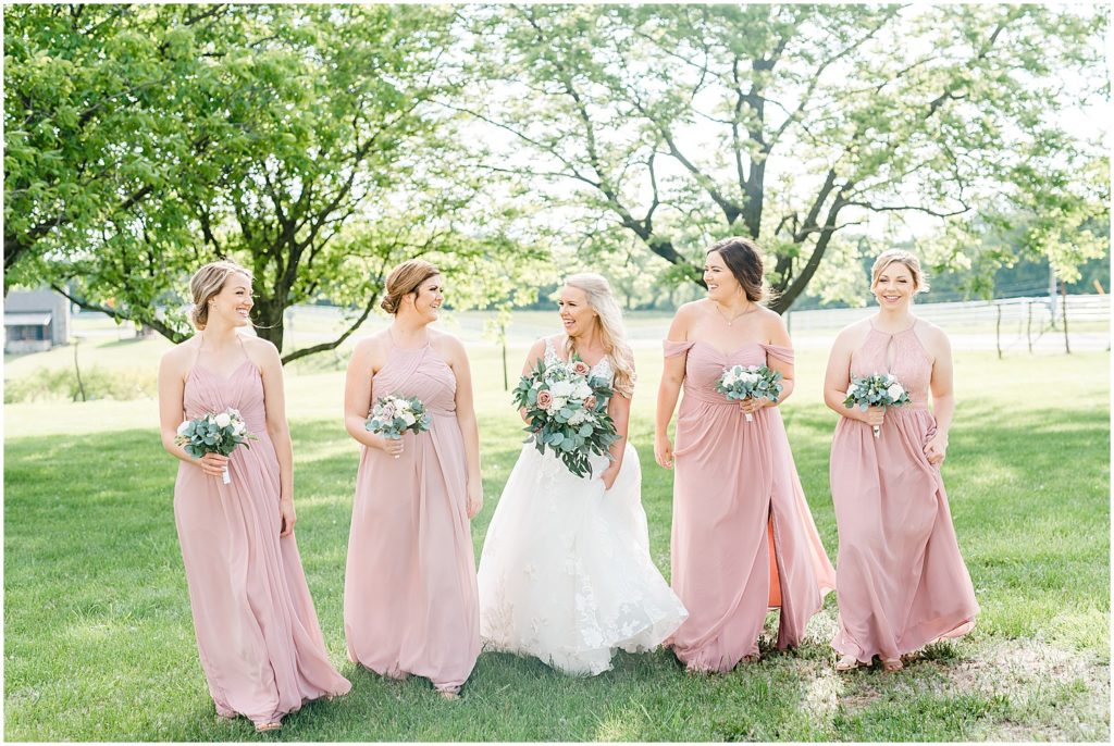 bride walking with bridesmaids in grass
