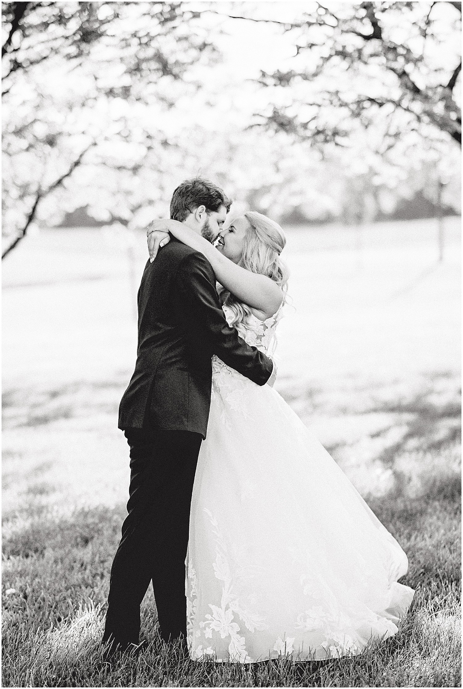 black and white image of bride and groom hugging and kissing under trees for cooper's ridge wedding