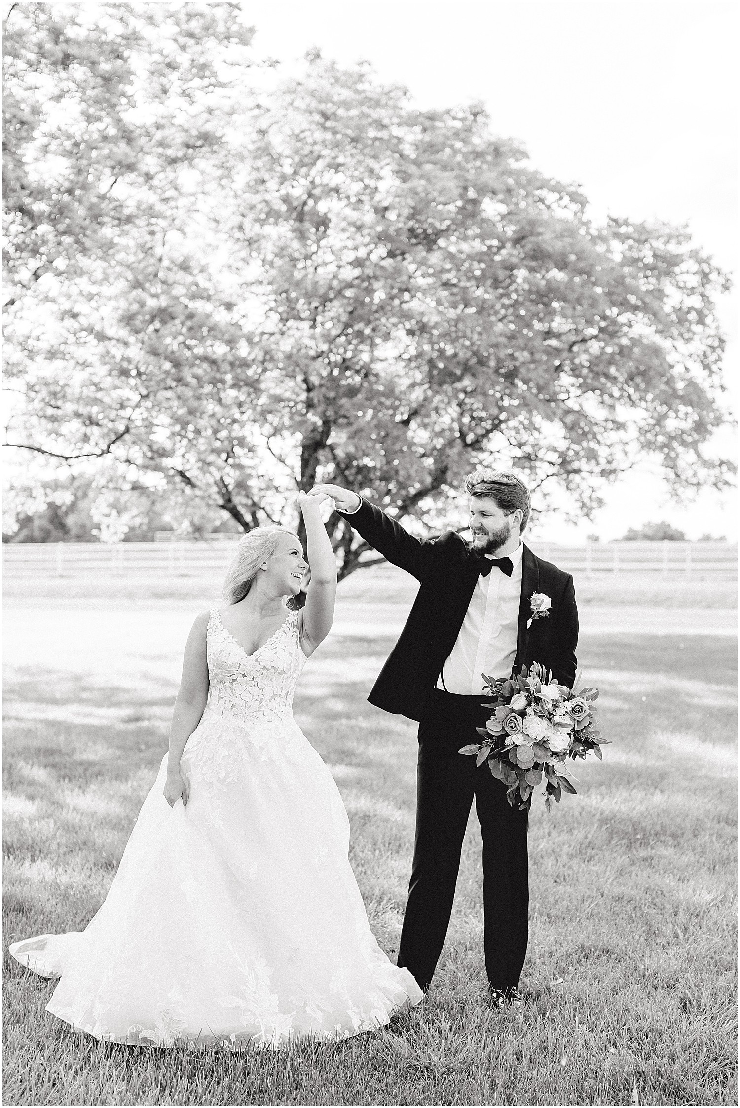 black and white image of bride and groom dancing under trees on wedding day