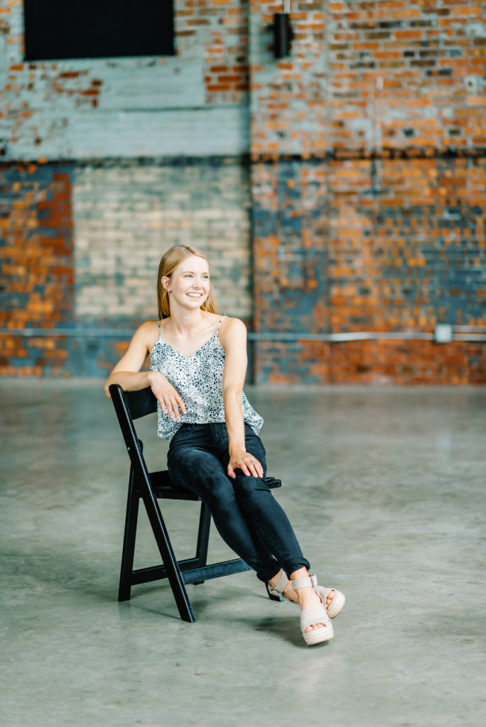 young woman sitting on black chair on concrete floor with brick walls at the millbottom wedding venue