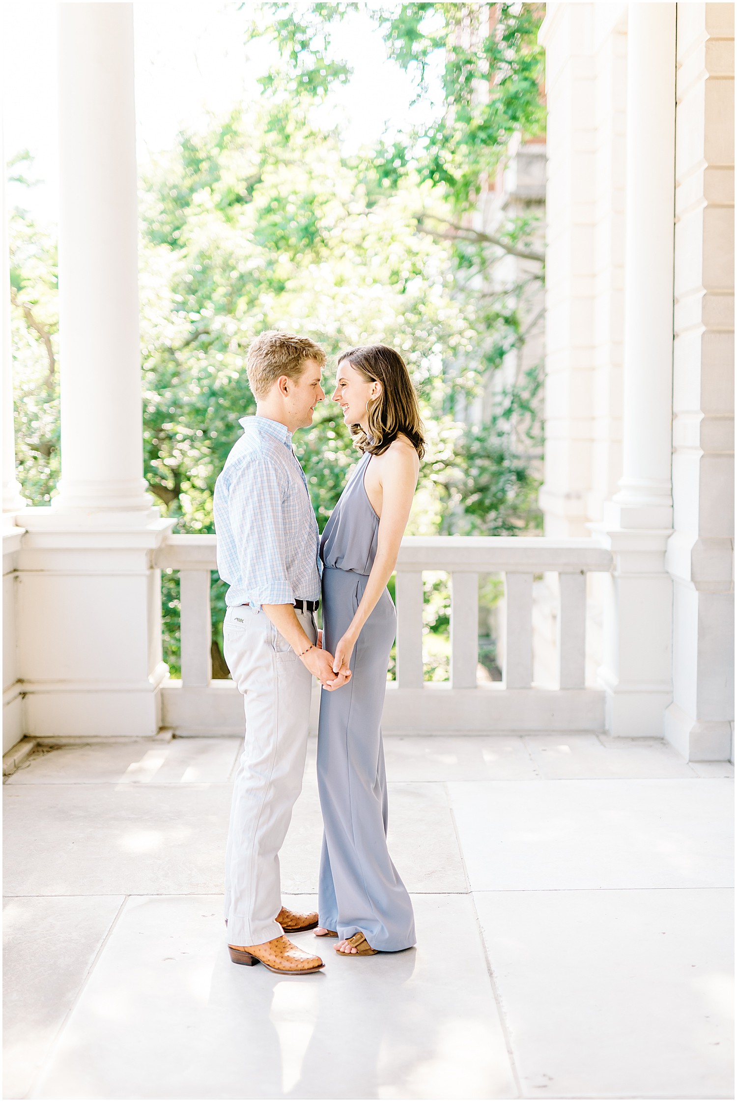 young couple in spring colors holds hands and smiles under porch on mizzou campus