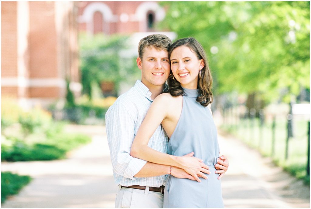 young couple holds each other on sidewalk for mizzou campus engagement pictures