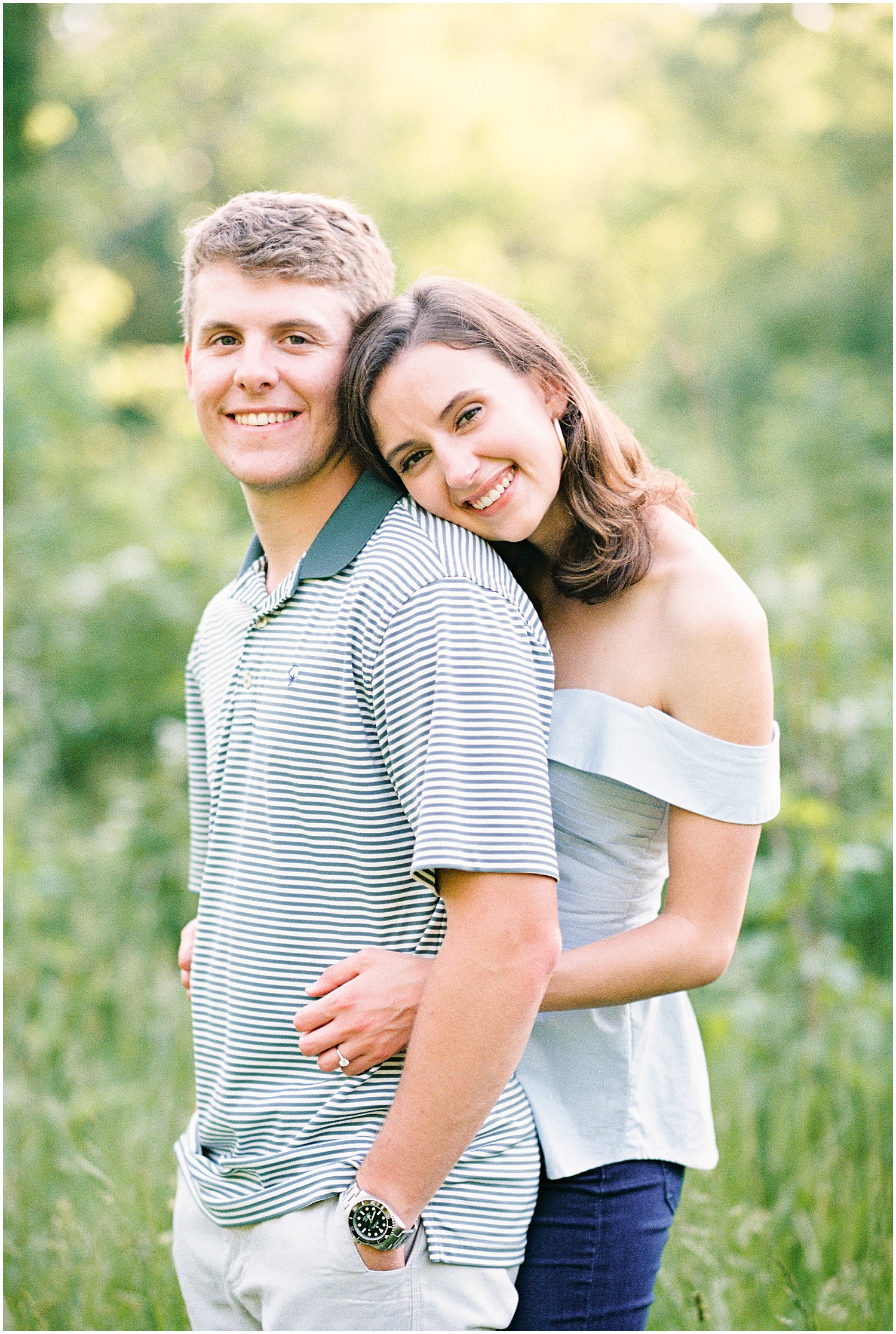 couple hugs in tall grass for engagement pictures in columbia, mo