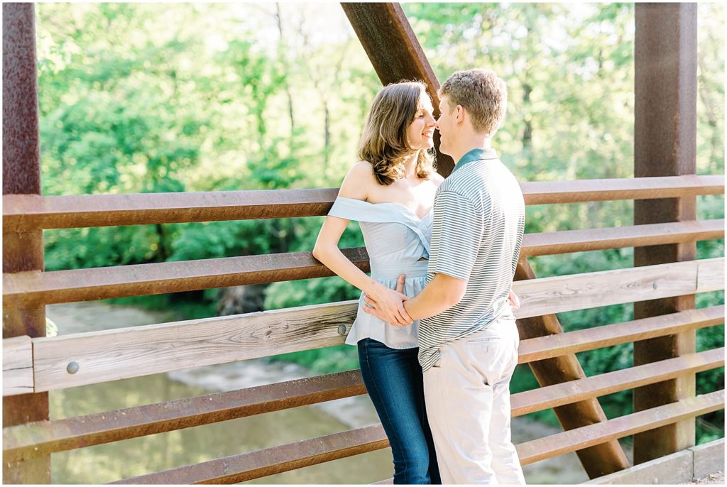 couple stands on bridge and kiss at capen park in columbia, mo