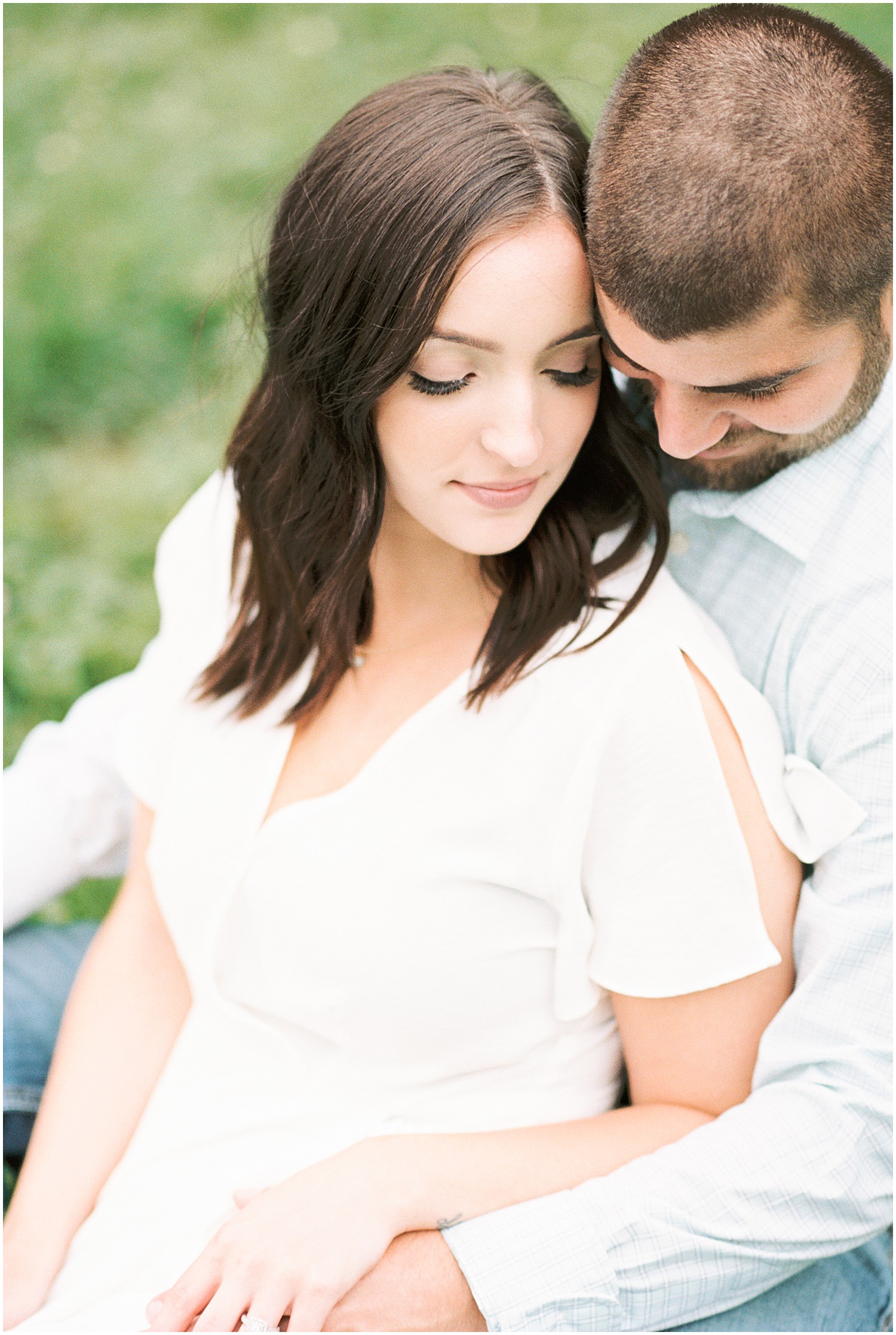 couple sitting on the grass cuddling for engagement session