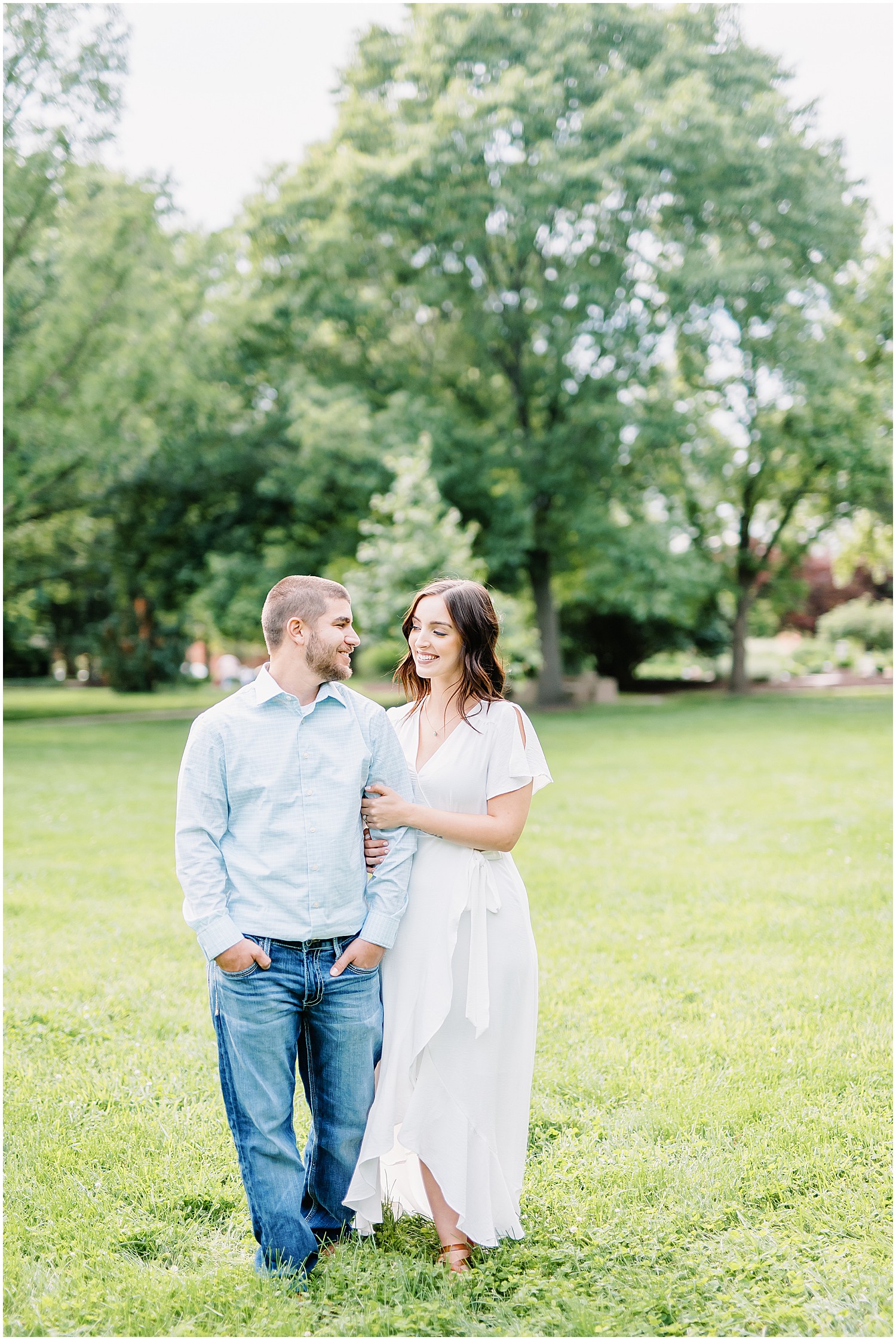 couple walking together arm in arm through the grass at shelter gardens for engagement session