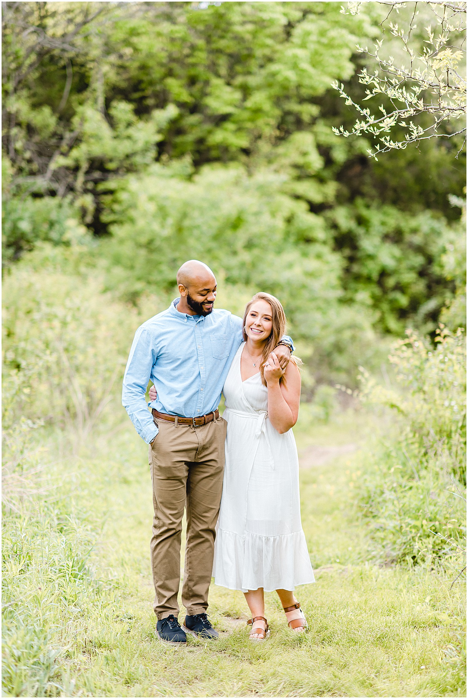 couple laughs together on grass path during jefferson city engagement session at greenway trail