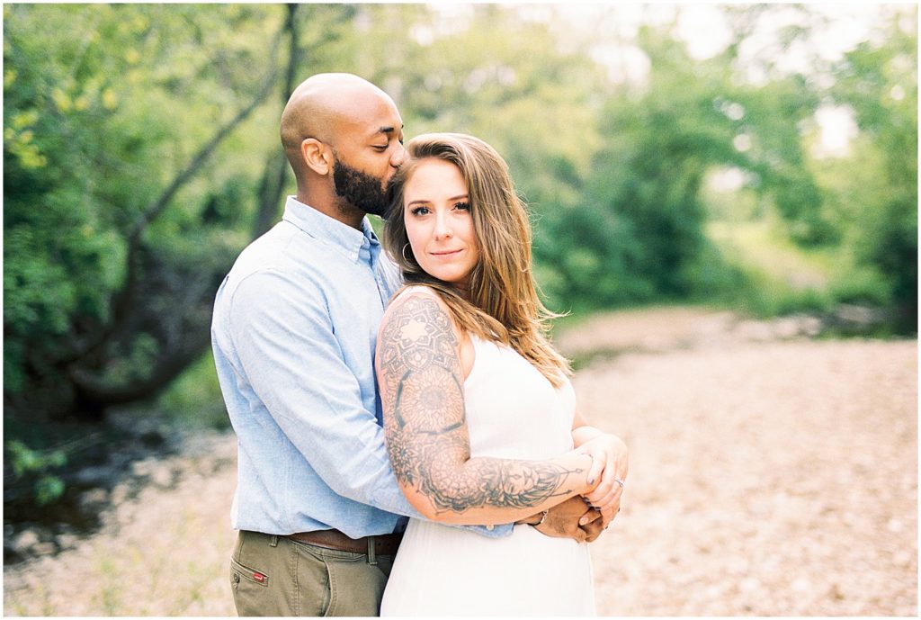 couple hugs each other in creek bed for jefferson city engagement session