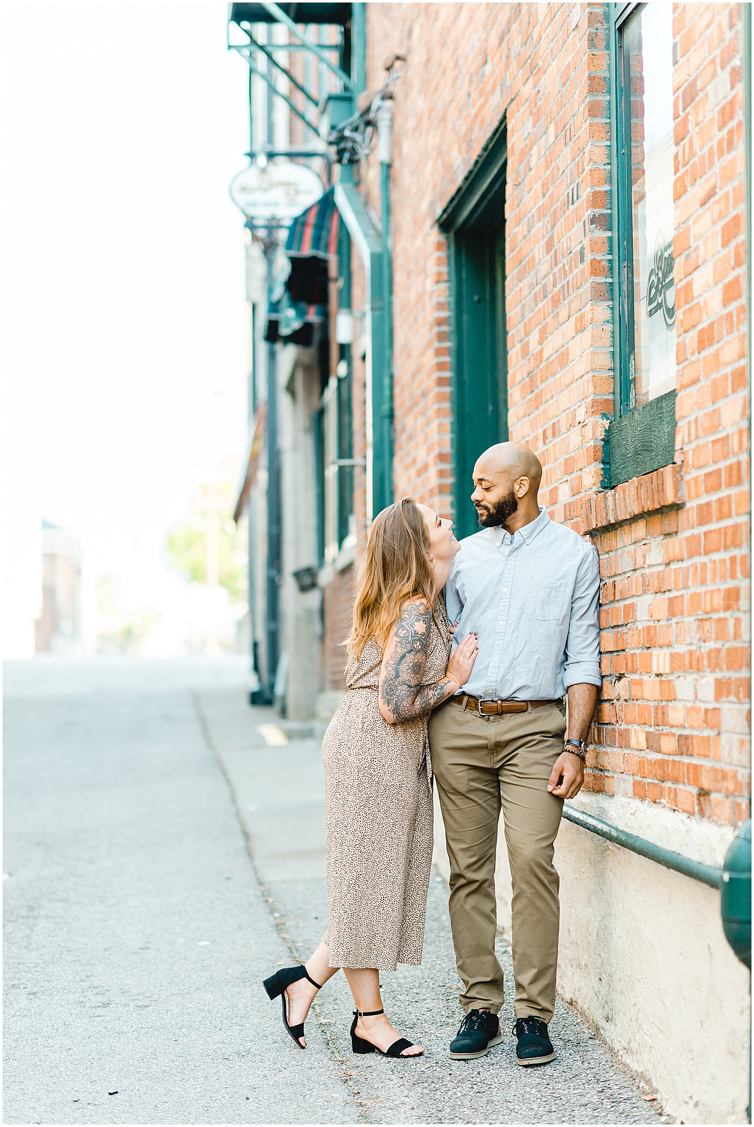 engaged couple lean against brick wall in downtown jefferson city