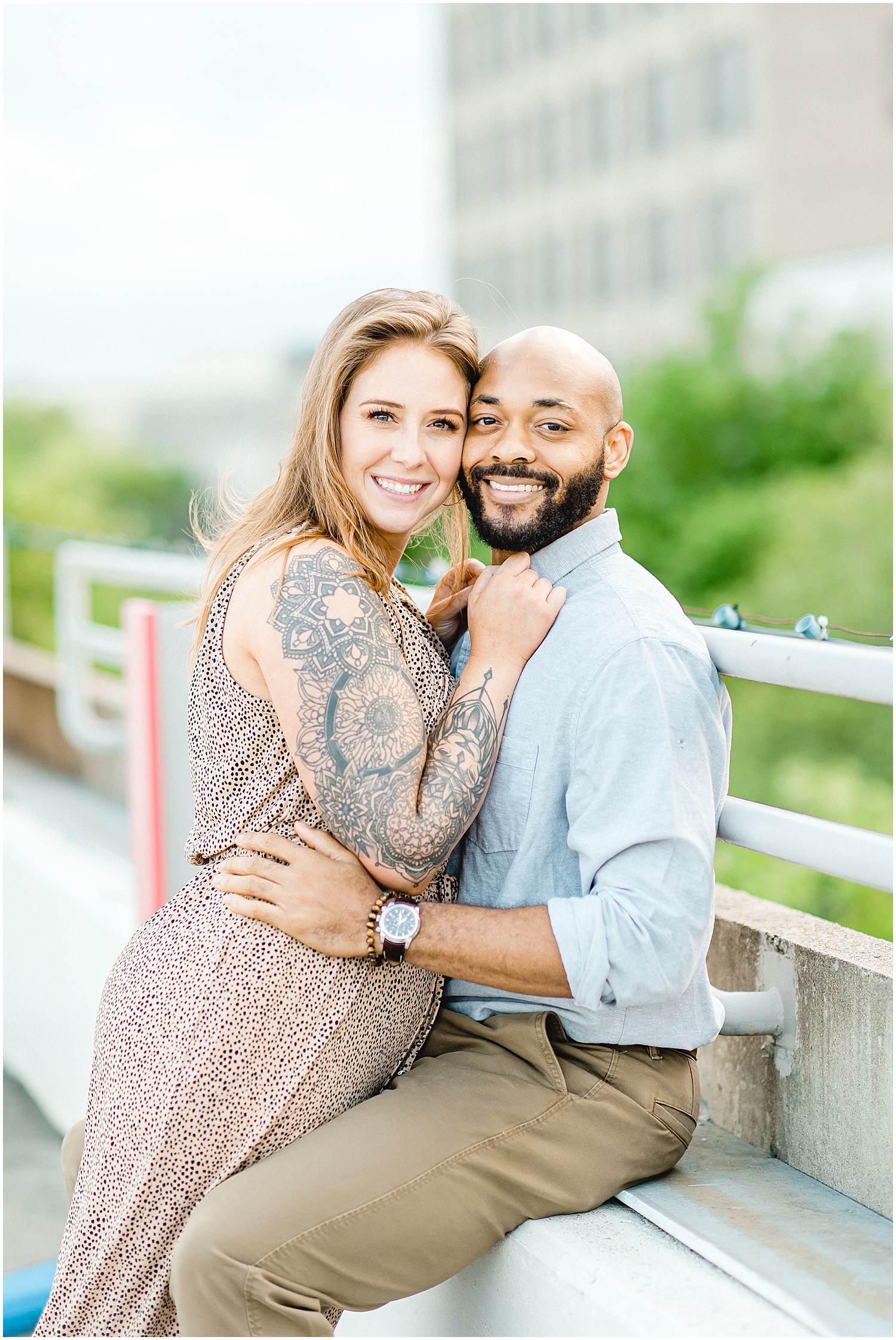 couple smiles for camera on parking garage for engagement pictures