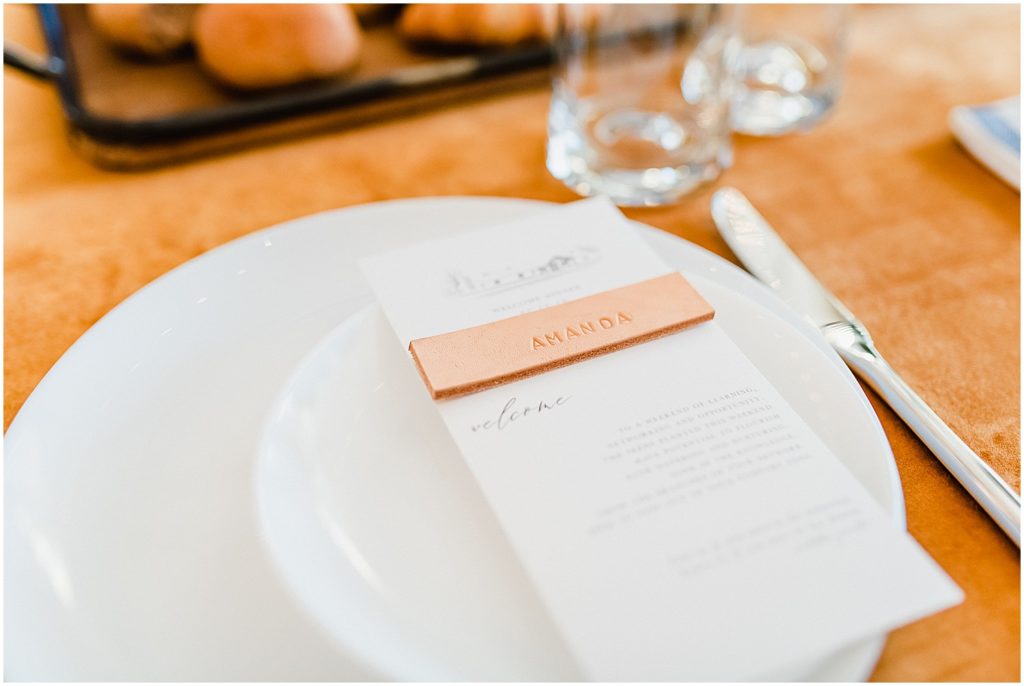 white plates and a leather name tag on a dinner table covered with leather tablecloth