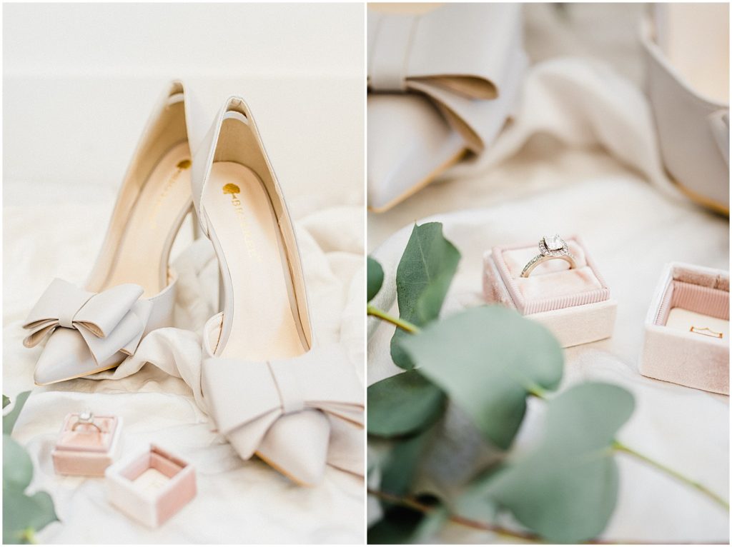 ivory wedding heels and a large diamond ring in a pink ring box sit upon an ivory silk