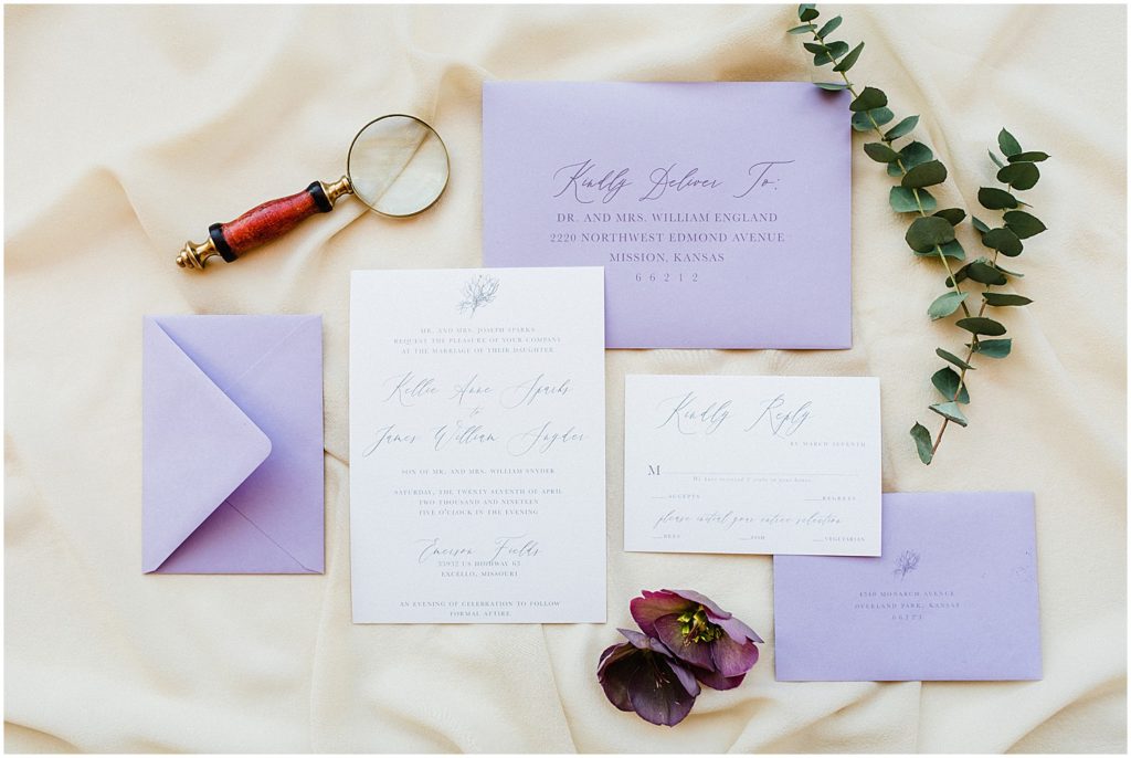 an invitation suite featuring calligraphy and purple envelopes