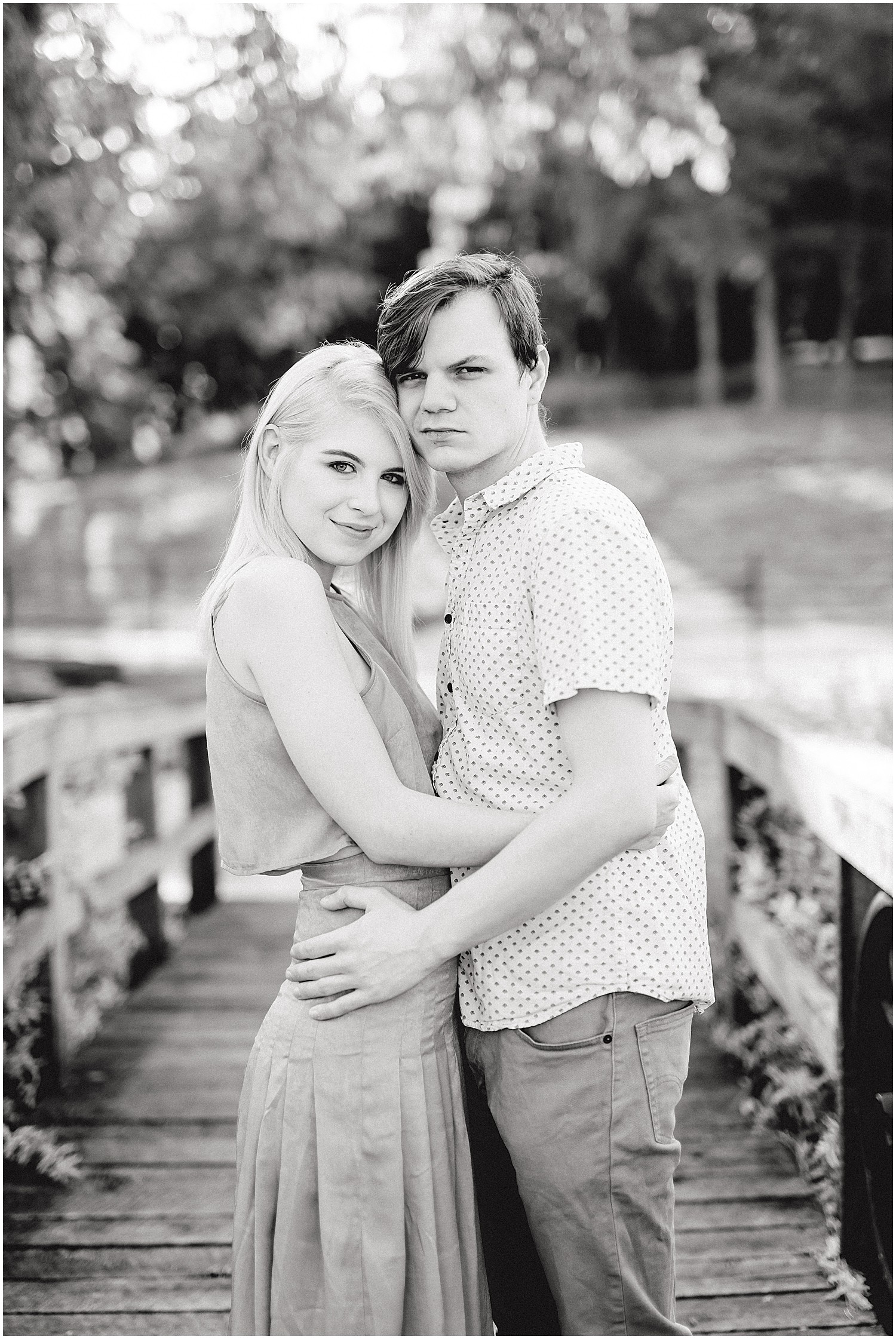 black and white image of young engaged couple hugging and smiling for pictures