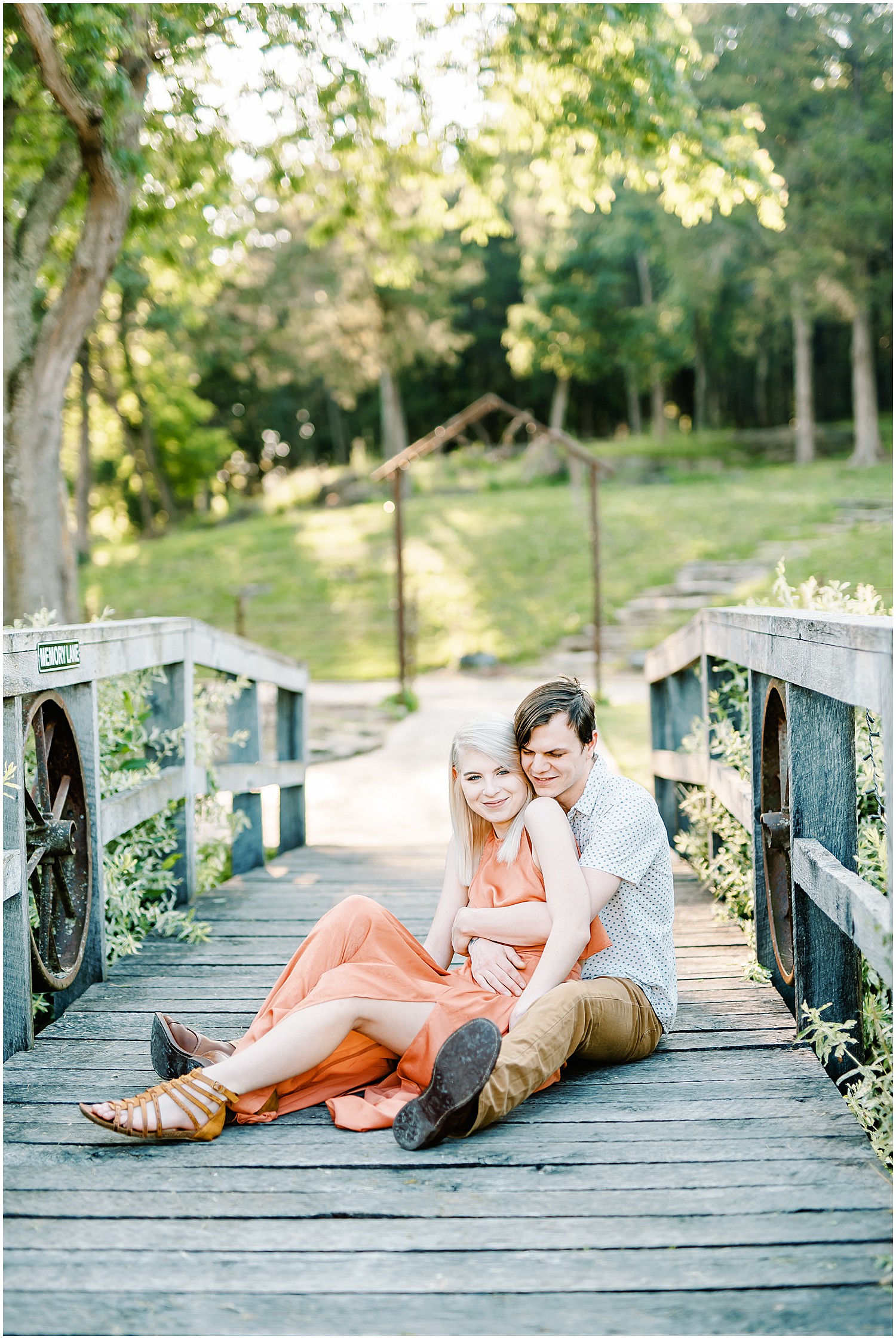 young couple snuggles on bridge at kempkers back 40 for engagement session