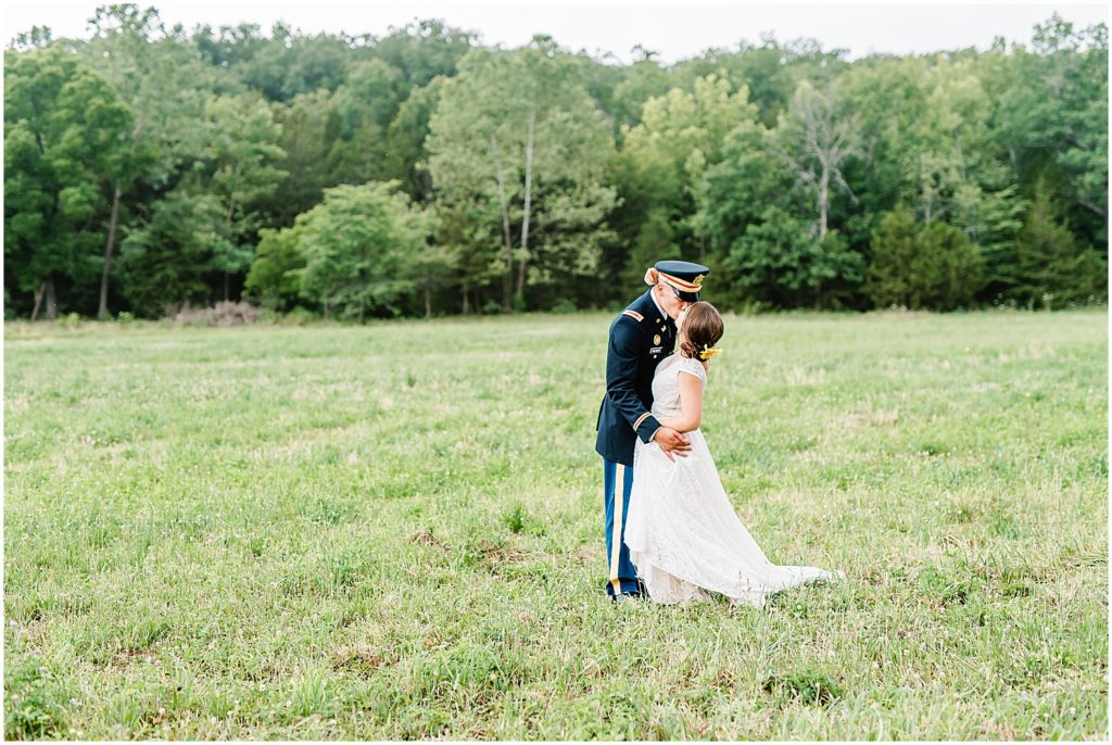 bride and groom kiss in a field during wedding day