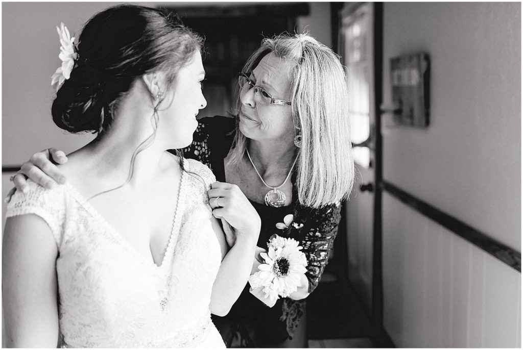 black and white image of mom crying while she looks at her daughter in her wedding gown on wedding day