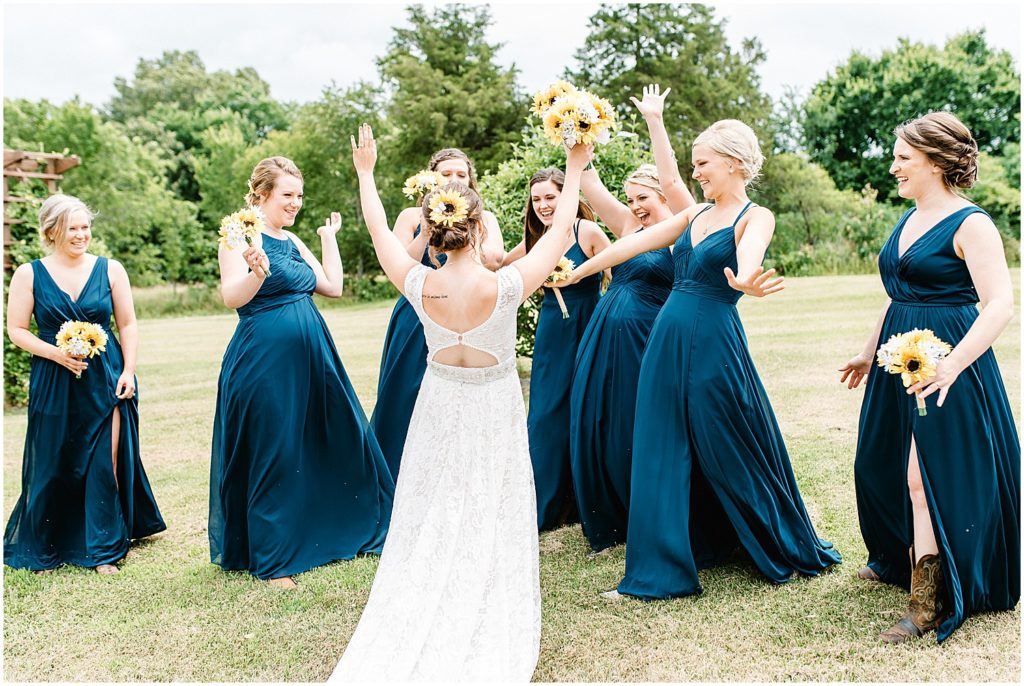 bride is greeted by bridesmaids in long navy dresses after getting in her wedding gown