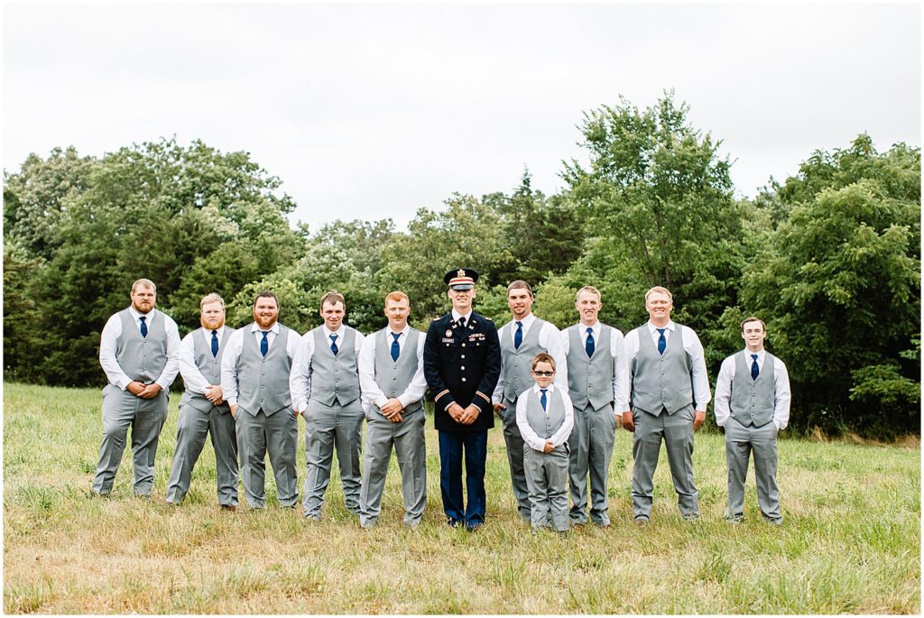 groom and groomsmen standing together in a field for wedding party portraits