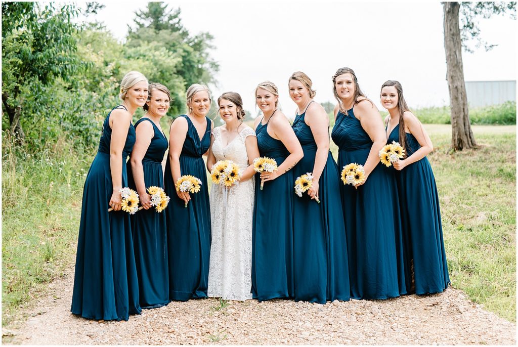 bridal party portrait of bridesmaids in long navy dresses holding sunflower bouquets