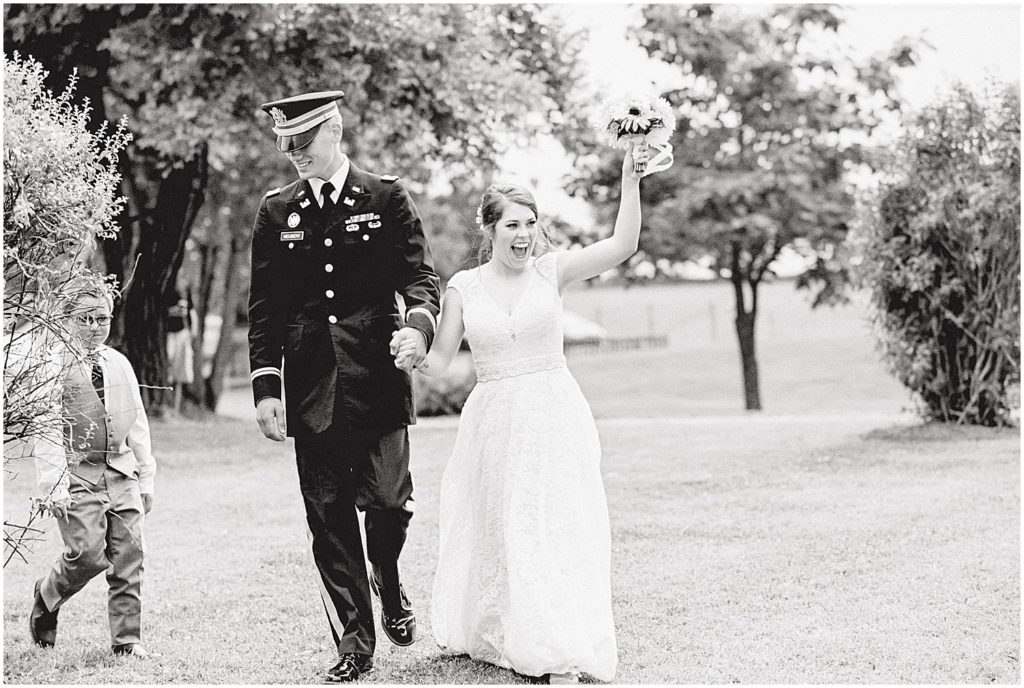 black and white image of bride and groom smiling and entering wedding reception