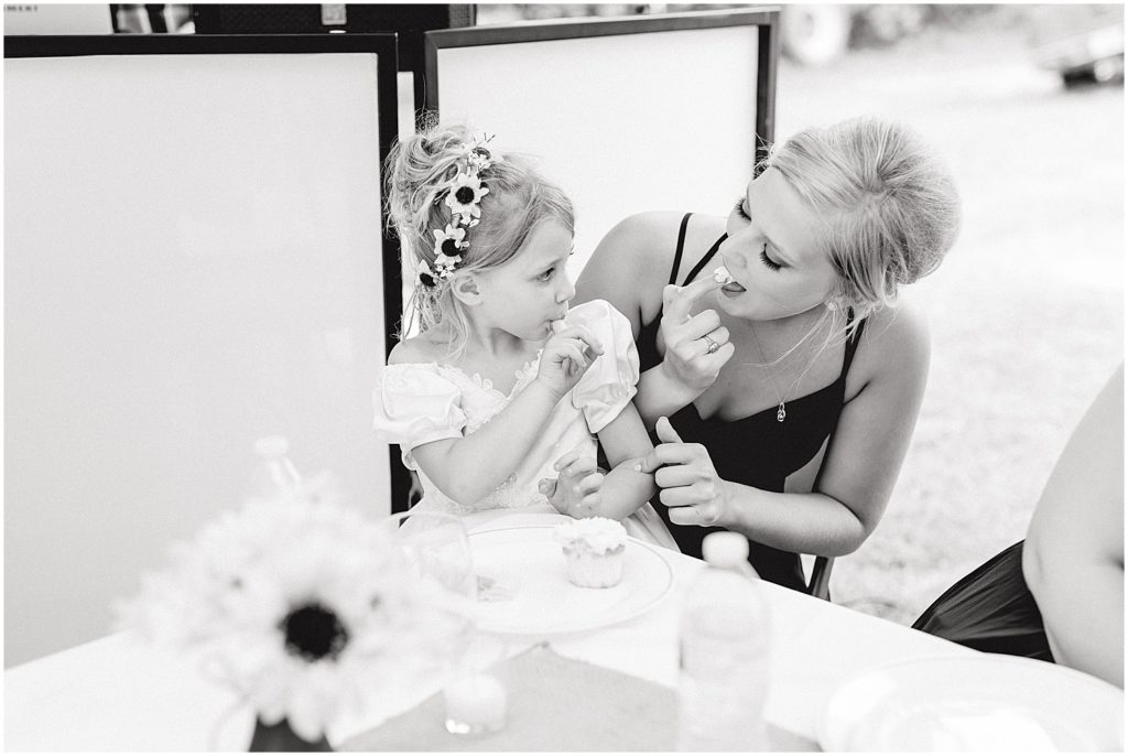 black and white image of bridesmaid and nieces eating cake at wedding reception in vienna, mo