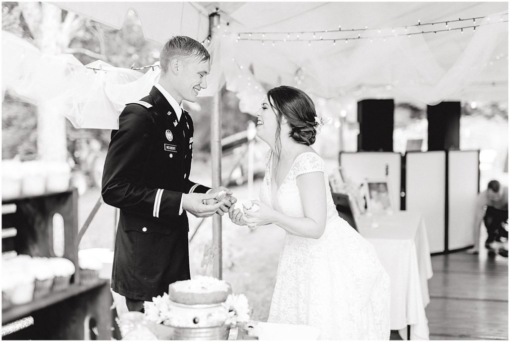 black and white image of bride and groom laughing after cutting the cake at wedding reception