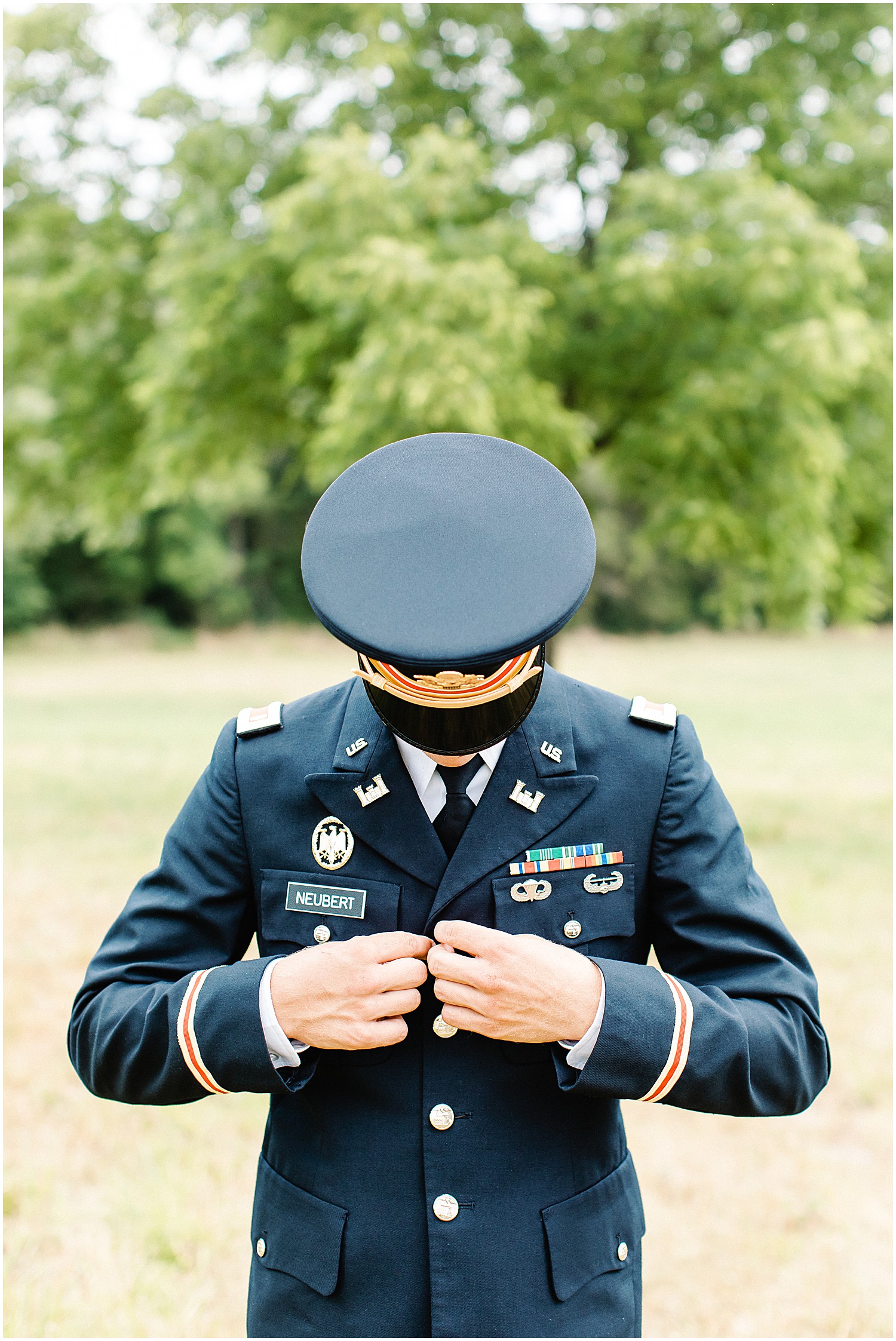 groom buttoning his dress blues before his wedding day in vienna, mo