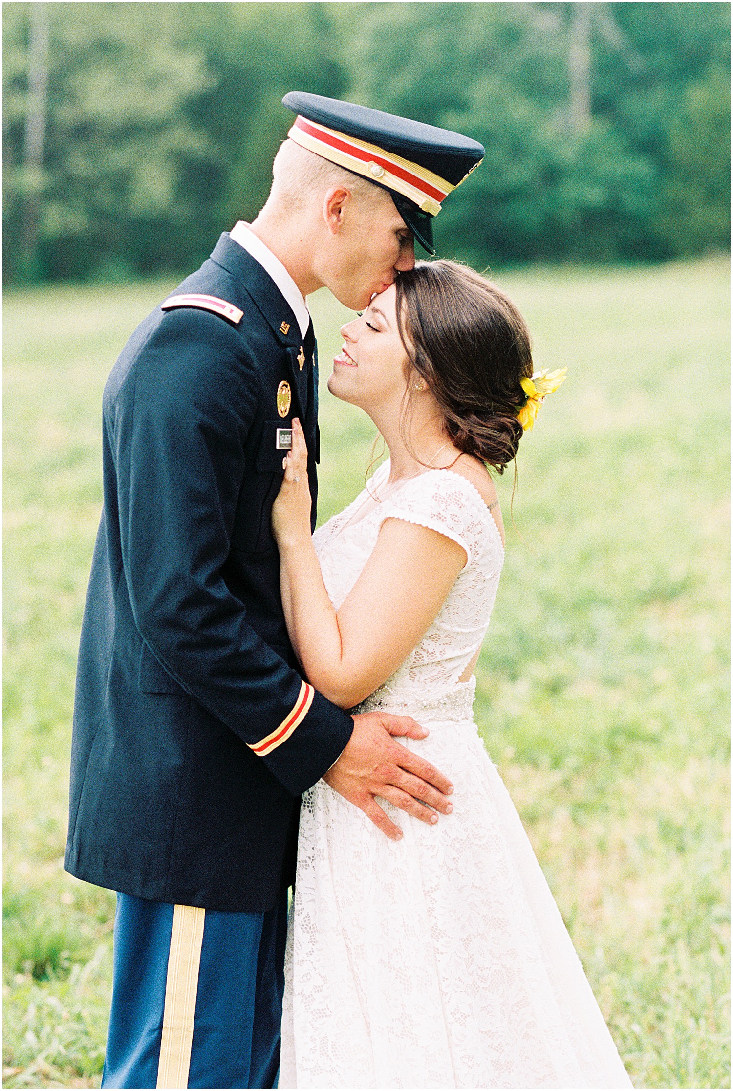 bride smiles as groom kisses her forehead in grassy field on wedding day in vienna, mo
