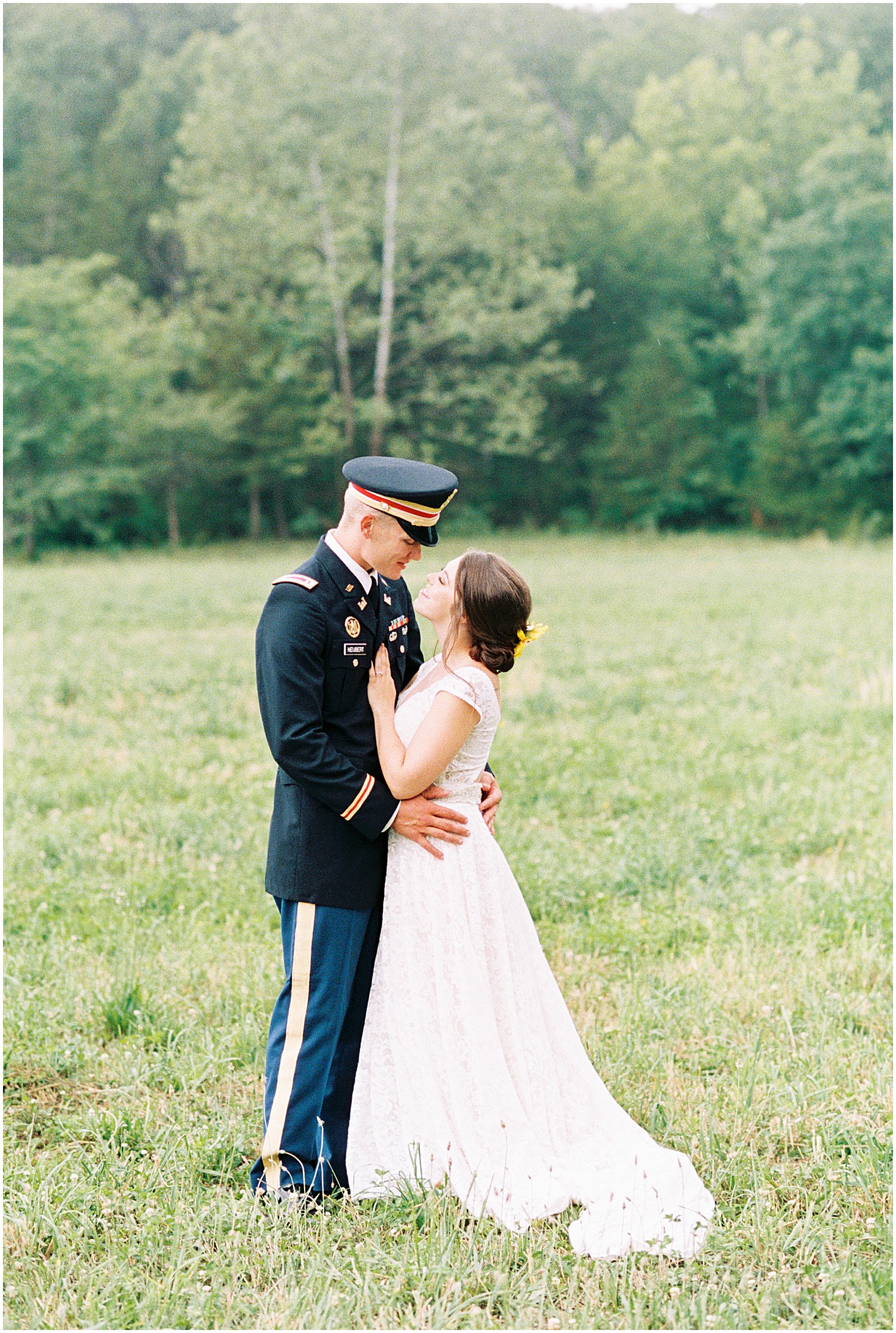 film image of bride and groom smiling at each other in grassy field on wedding day