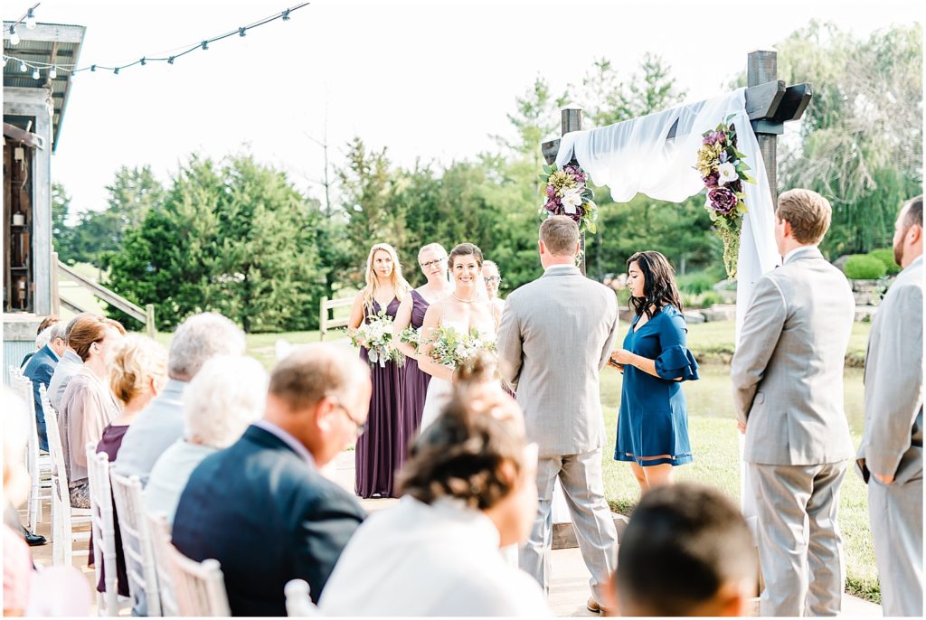a bride smiles at her groom during outdoor wedding ceremony 