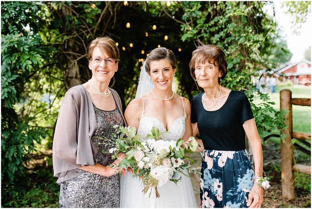 a bride with her mother and grandmother smile at the camera