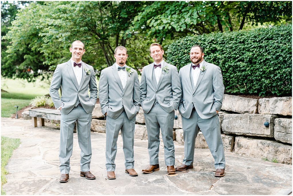 groom and groomsmen in gray tuxes smile at the camera for wedding party portraits