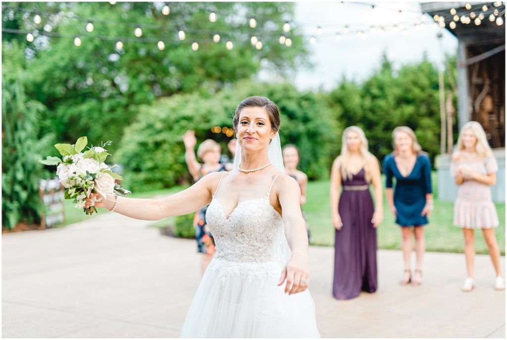 bride prepares to throw her bouquet for bouquet toss during outdoor wedding reception