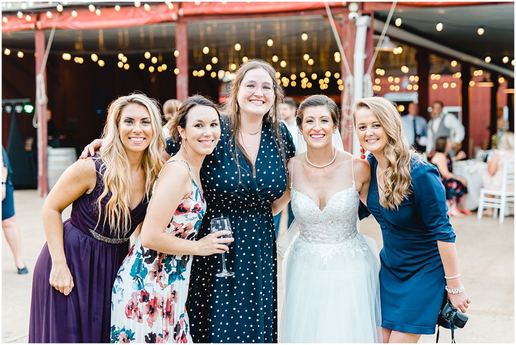 bride smiles with a group of friends for a photo during wedding reception