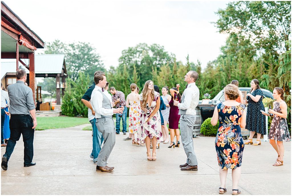wedding guests dance on concrete patio during cedar lake cellars wedding reception