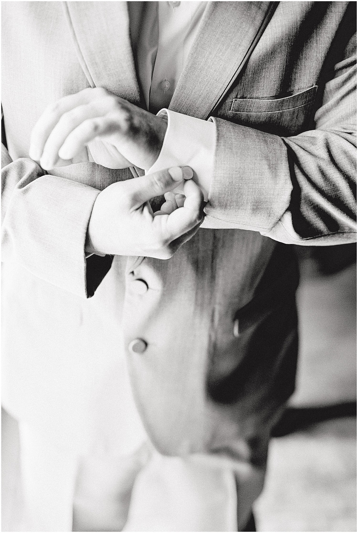 black and white image of a groom adjusting his cuff links on his wedding day at cedar lake cellars