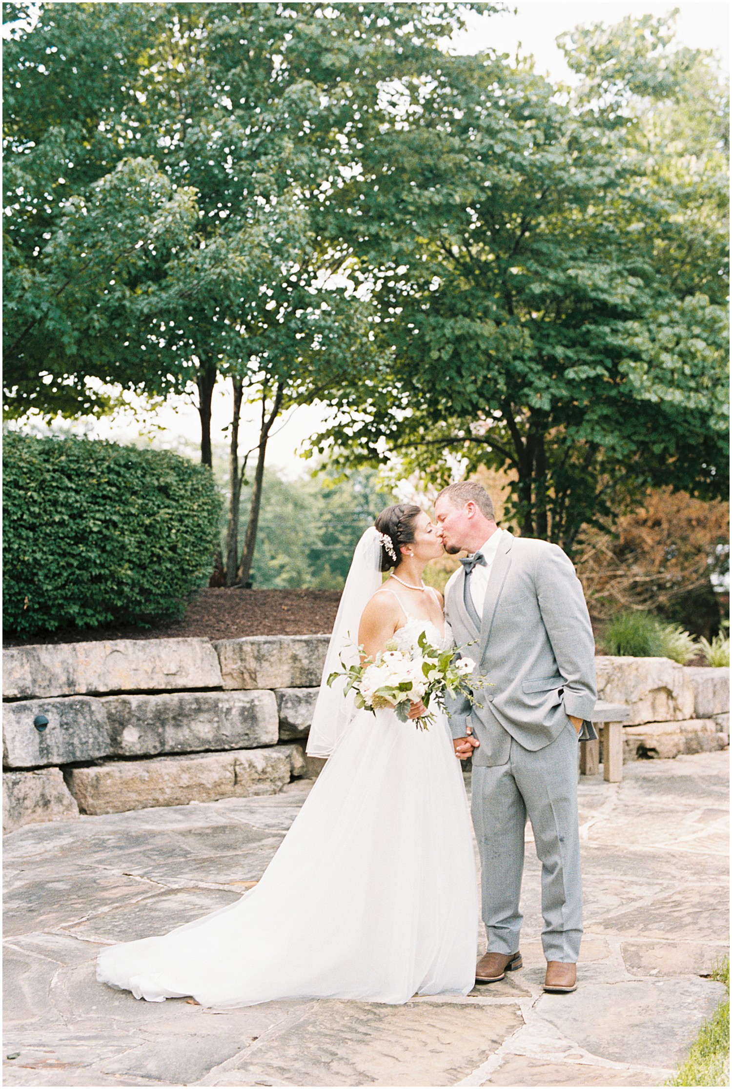 a bride and groom kiss on a rock patio during bride and groom portraits on their wedding day
