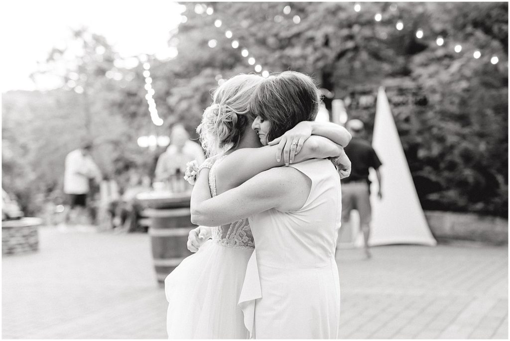 black and white image of bride and mother hugging during dance on patio at little piney lodge in Hermann, mo