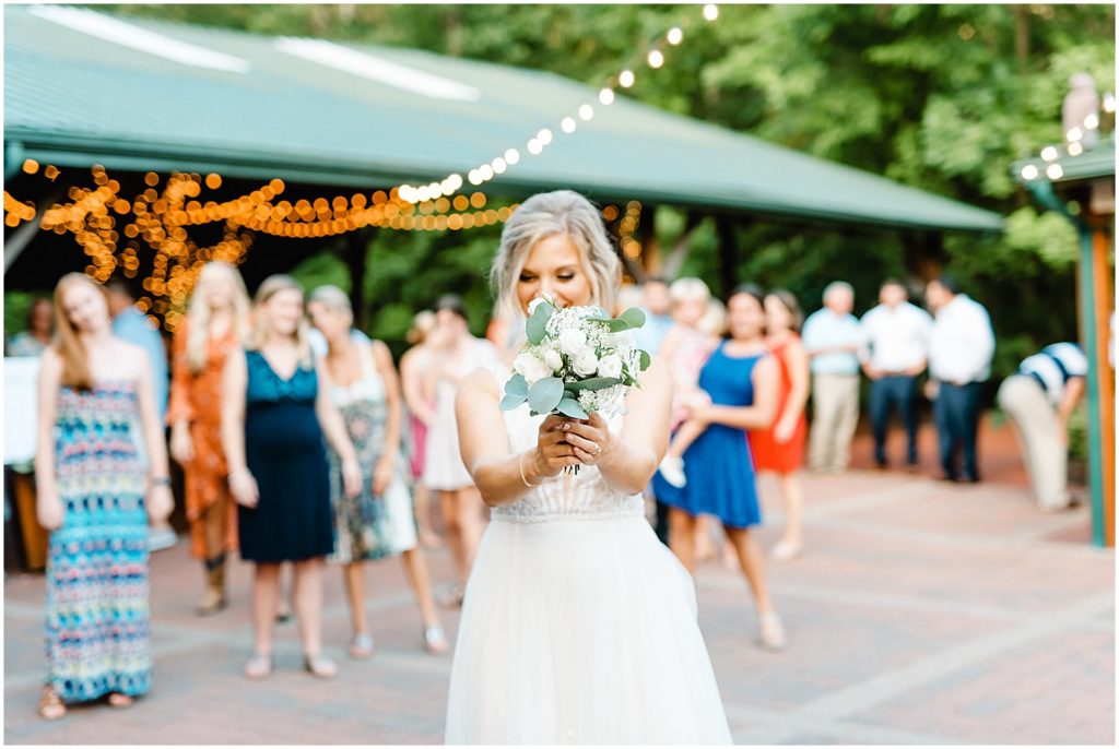bride gets ready to toss bouquet during wedding reception on patio